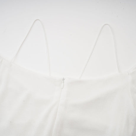 A white offshoulder maxi dress with panel detailing worn by a model standing against a plain background