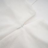 A white offshoulder maxi dress with panelled design worn by a model standing against a plain background