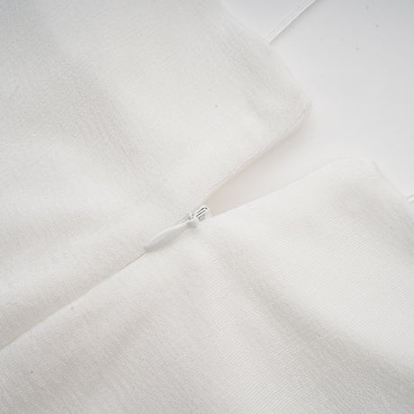 A white offshoulder maxi dress with panelled design worn by a model standing against a plain background