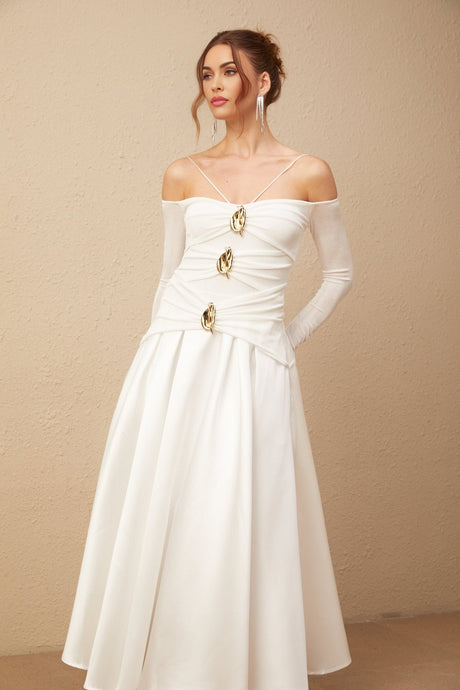 A white offshoulder maxi dress with panelling worn by a model standing against a plain background