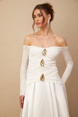 A white offshoulder maxi dress with panels worn by a model standing against a plain background