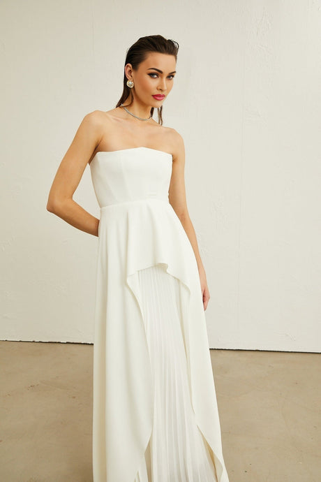 A white offshoulder maxi dress with pleated details worn by a model named Vanessa