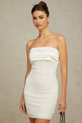 A white offshoulder mini dress with sequin embellishments on a model against a plain background