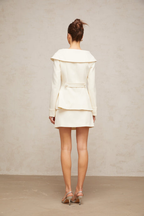 A white peplum jacket paired with a matching skirt creating an elegant two piece ensemble