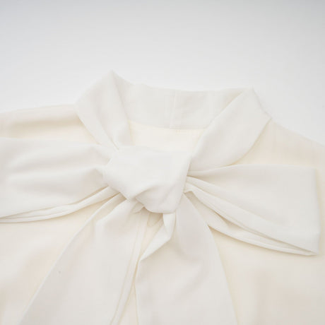 A white pleated jacket and dress set with embellishments featuring a matching design The jacket is worn over the dress creating an elegant coordinated outfit