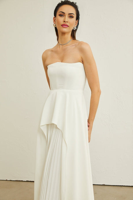 A white pleated maxi dress with an offshoulder neckline worn by a model named Vanessa