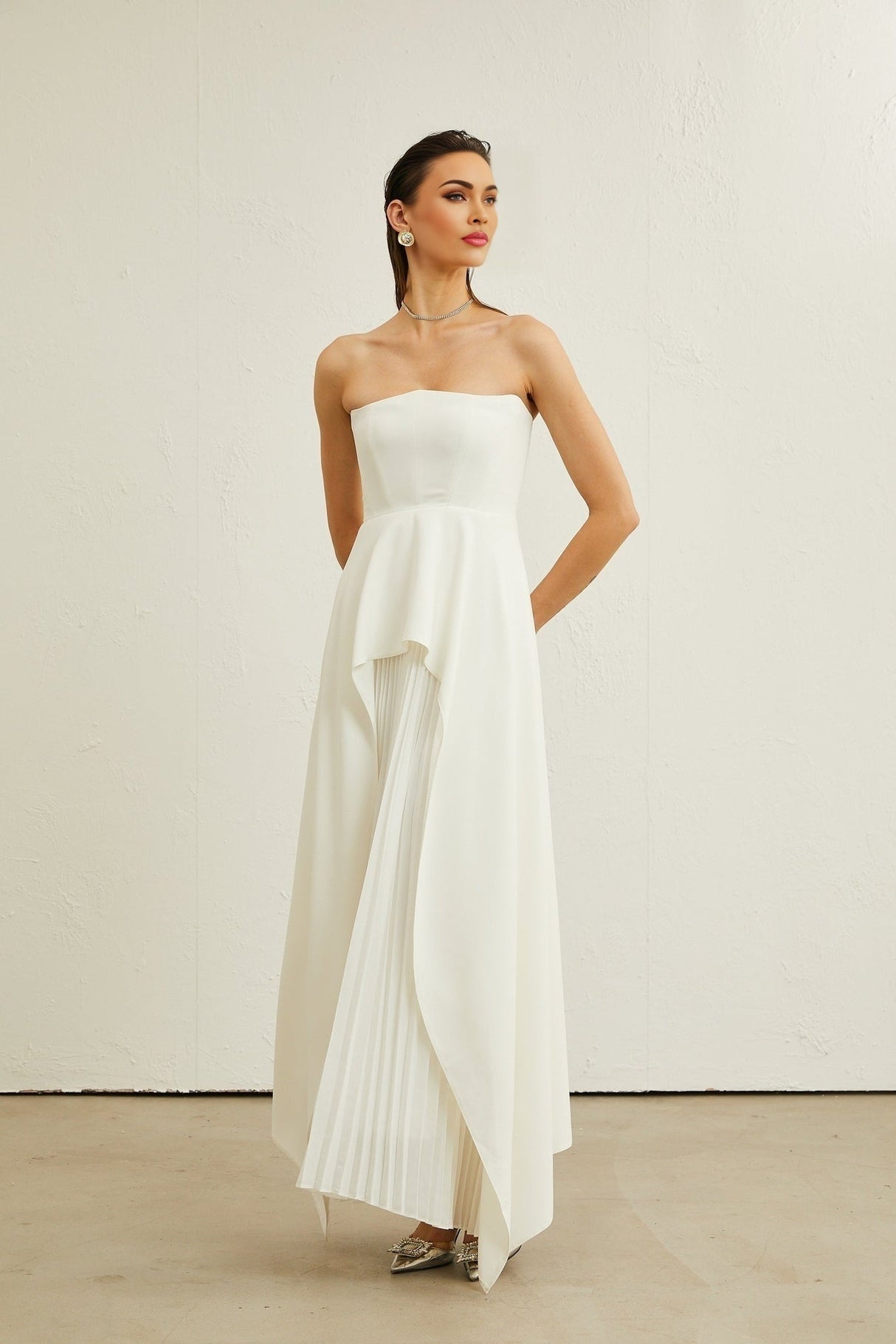 A white pleated maxi dress with an offshoulder neckline worn by a model named Vanessa