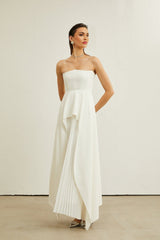 A white pleated maxi dress with an offshoulder neckline worn by a model named Vanessa