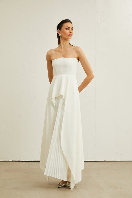 A white pleated maxi dress with an offshoulder neckline worn by a model named Vanessa