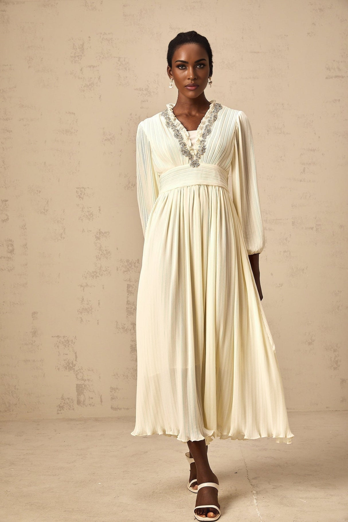 A white pleated midi dress with crystal trim detailing along the neckline and waist named Yana