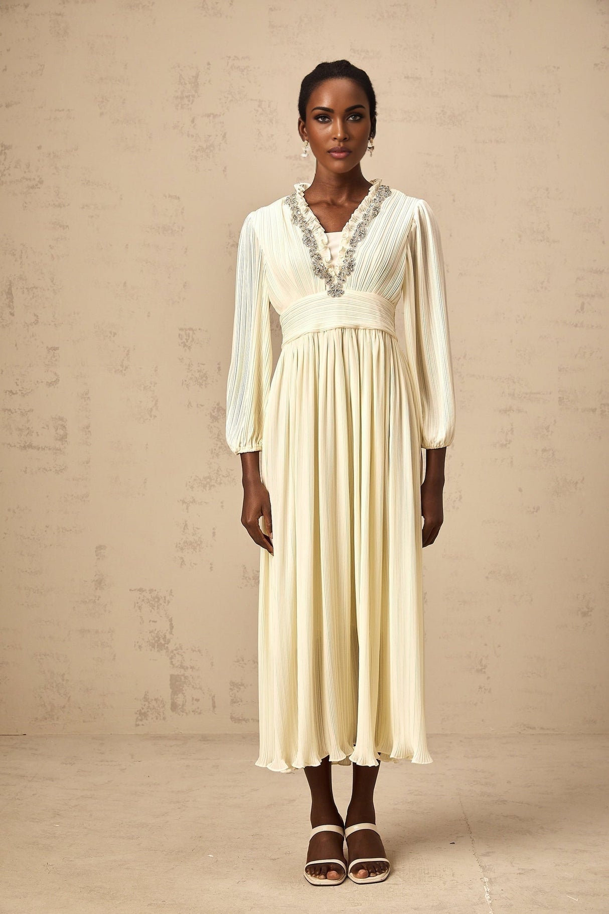 A white pleated midi dress with crystal trim detailing named Yana