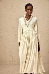 A white pleated midi dress with crystal trim details along the neckline and waist featuring a sleeveless design and flowing skirt
