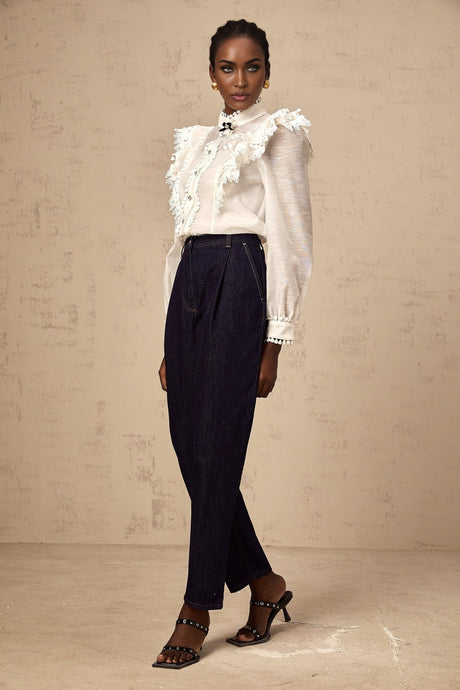 A white semi sheer shirt with delicate lace trim details named Capucine hanging on display