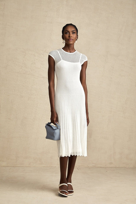 A white semisheer midi dress with scalloped hem details and a delicate flowy silhouette named Liane