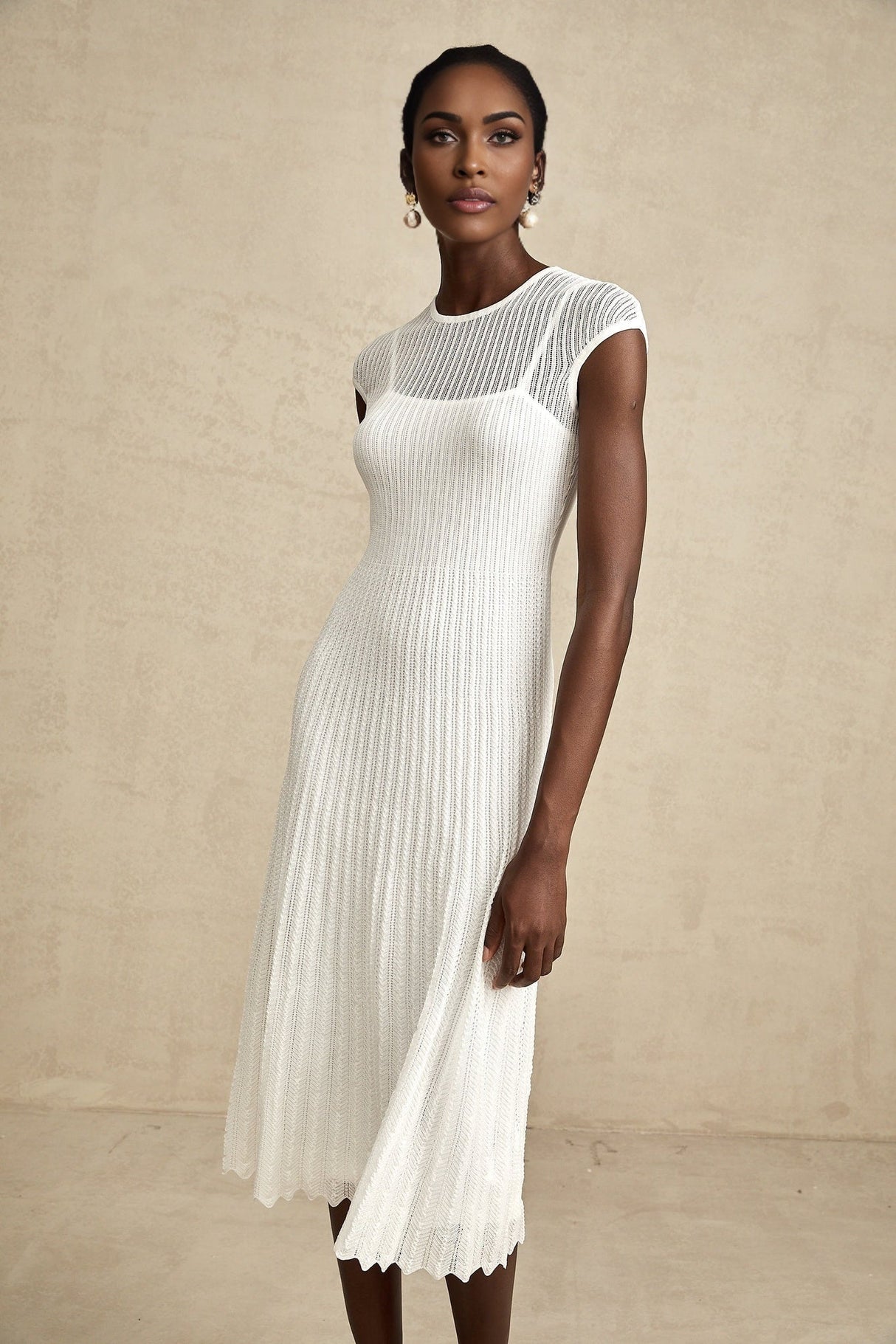 A white semisheer midi dress with scalloped hem details and delicate lace patterns named Liane
