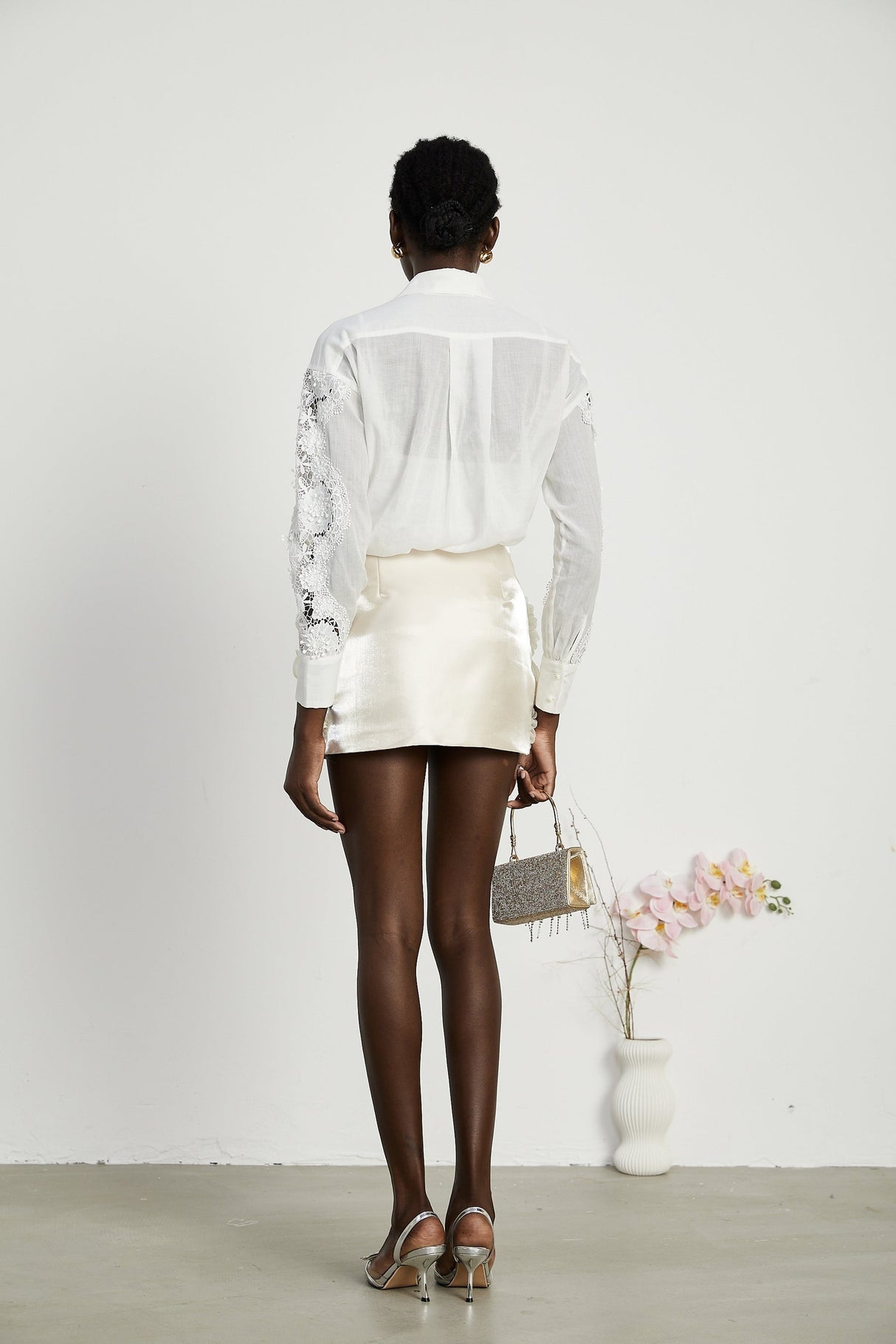 A white shirt with lace embroidery details and cut out sections visible on the sleeves and body