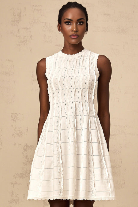 A white sleeveless knit mini dress with ruffled details worn by a model standing against a plain background
