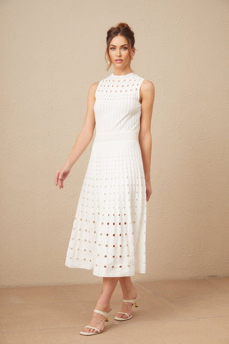 A white sleeveless knitted midi dress with cutout details worn by a model standing against a plain background