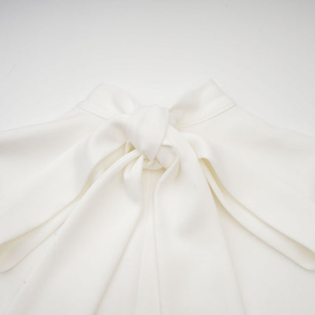 A white sleeveless maxi dress with a bow and decorative artificial flowers named Magali