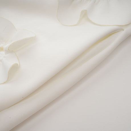 A white sleeveless maxi dress with a bow and decorative artificial flowers named Magali