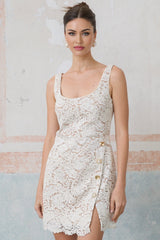 A white sleeveless mini dress made of corded lace featuring a fitted silhouette and delicate floral pattern throughout