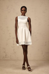 A white sleeveless mini dress with cutout details and a knitted texture featuring a formfitting silhouette