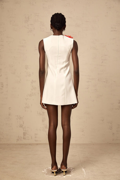 A white sleeveless mini dress with three dimensional petal details featuring a floral inspired texture and a short hemline