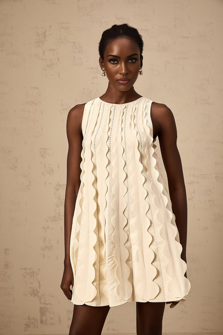 A white sleeveless mini dress with wavy detailing named Axelle on a plain background