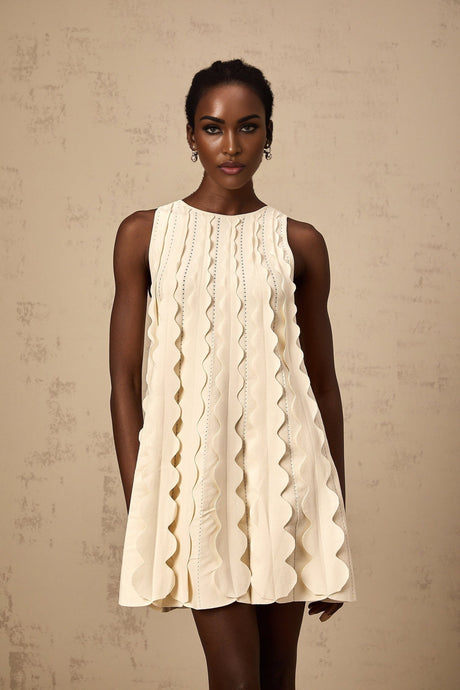 A white sleeveless mini dress with wavy details on a female model named Axelle