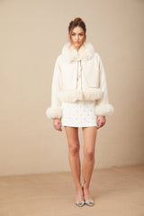 A white suede short coat with fur trim and padded lining worn by a model against a plain background