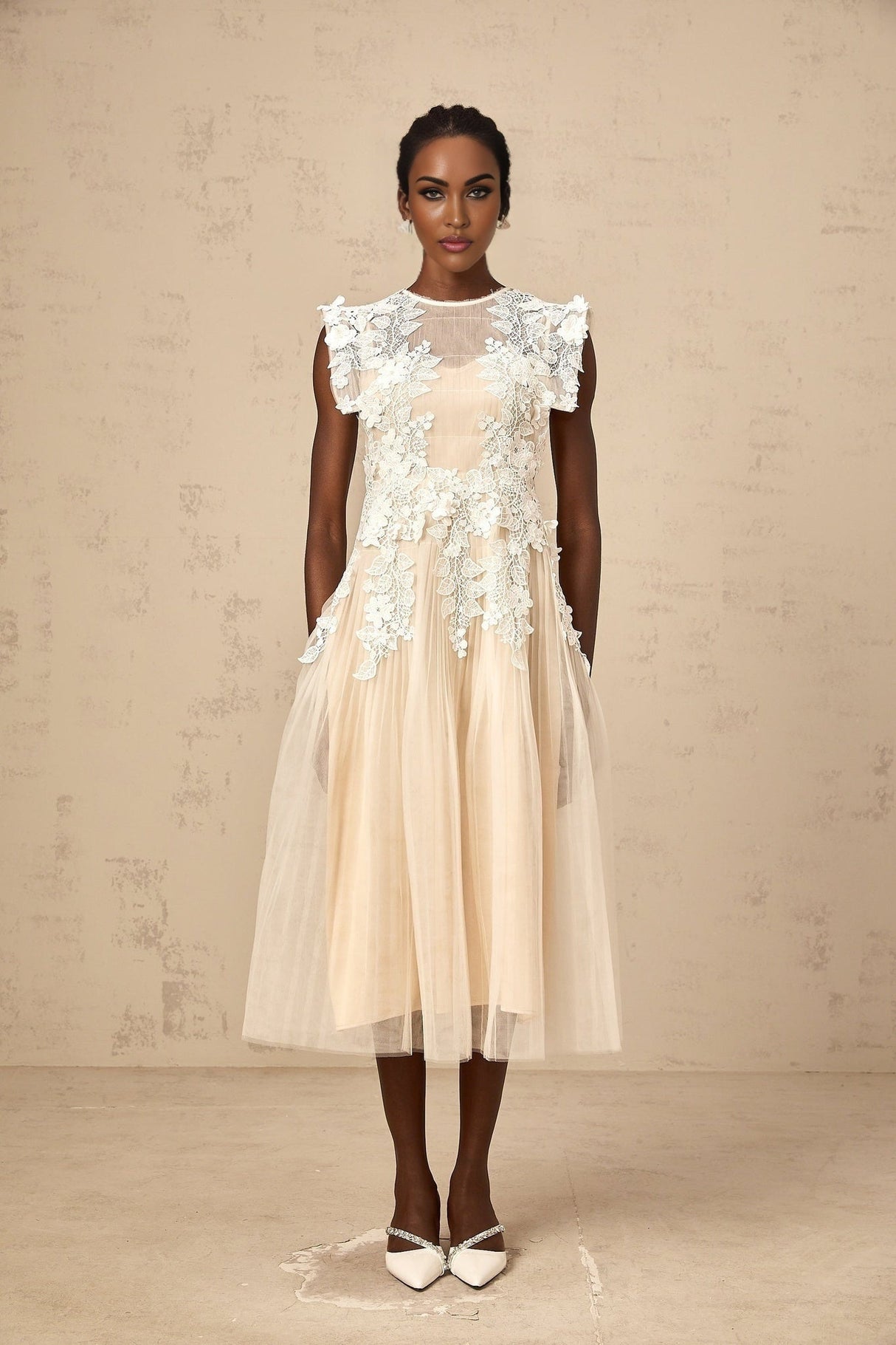 A white tulle midi dress with delicate flower appliques scattered across the bodice and skirt featuring a fitted waist and flowing silhouette