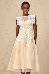 A white tulle midi dress with floral appliques scattered across the bodice and skirt featuring a fitted waist and delicate straps