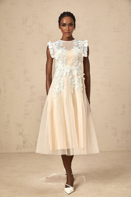 A white tulle midi dress with floral appliques scattered across the bodice and skirt featuring a fitted waist and flowing silhouette