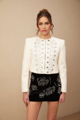 A white tweed jacket adorned with crystal embellishments featuring a classic design and textured fabric