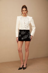 A white tweed jacket adorned with crystal embellishments featuring a tailored silhouette and classic design
