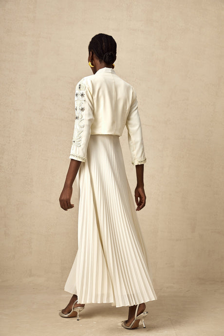 A white twopiece outfit featuring a pleated jacket and dress set with embellishments The jacket has decorative details and the dress matches in style and color Both pieces are designed to be worn together as a coordinated ensemble