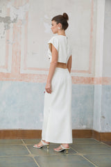 A white twopiece outfit featuring a sleeveless top and skirt set adorned with shell embellishments named Delphine