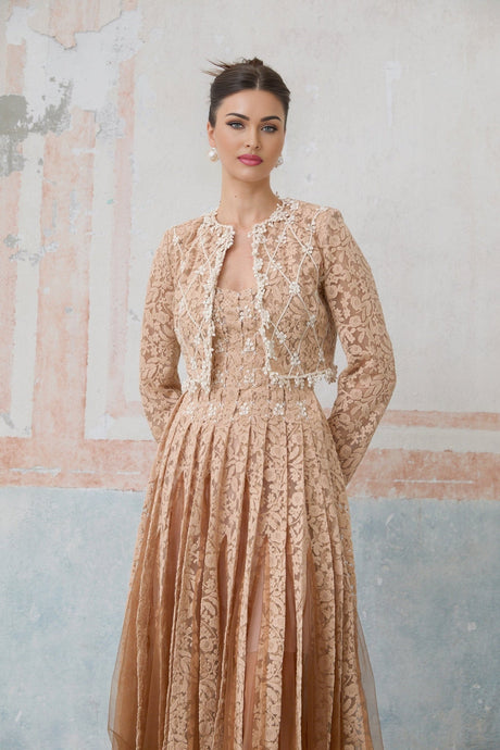 A woman wearing a beige crochet lace cardigan over a matching sleeveless dress standing in a neutral background