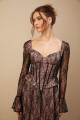 A woman wearing a black lace midi dress with a flared skirt and fitted bodice standing against a plain background