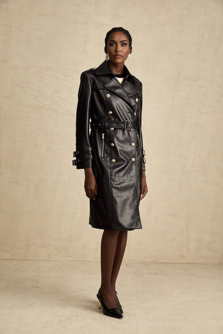A woman wearing a black leather coat with double breasted front buttons and a belt cinched at the waist