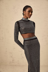 A woman wearing a black matching set consisting of a rhinestoneembellished mesh top and skirt Vera design