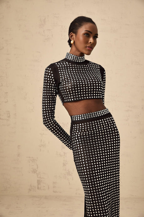 A woman wearing a black matching set consisting of a rhinestoneembellished mesh top and skirt Vera design