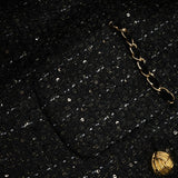 A woman wearing a black mini dress featuring a combination of tweed fabric and sequin panels The dress has a classic silhouette with short sleeves and a high neckline showcasing the contrast between the textured tweed and shimmering sequins