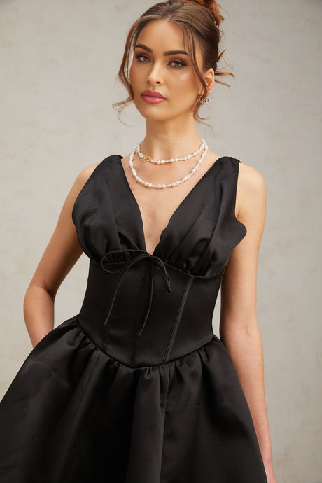 A woman wearing a black mini dress with a Vneckline and flared skirt