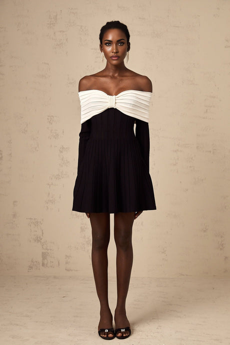 A woman wearing a black offshoulder mini dress with a bow detail and knit fabric