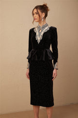A woman wearing a black velvet midi dress with embellishments standing in a neutral pose against a plain background
