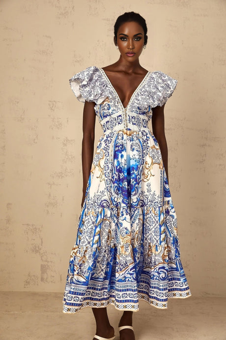 A woman wearing a blue midi dress with a baroque print pattern and tiered skirt design