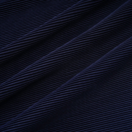 A woman wearing a blue patterned cape and matching skirt set Debbie model The cape is creased and flows over the shoulders The skirt is fitted and falls below the knee Both pieces feature a repeating print pattern in shades of blue