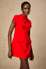 A woman wearing a bright red mini dress with cap sleeves standing in a relaxed pose