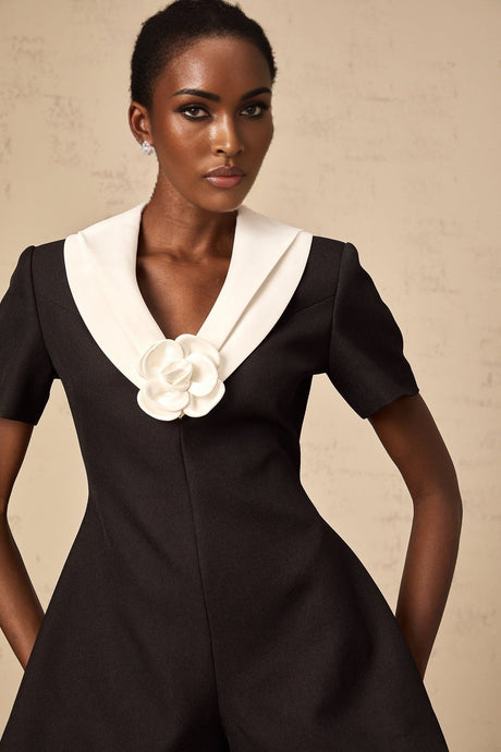 A woman wearing a colorblocked jumpsuit with floral appliqués featuring contrasting shades and a fitted silhouette